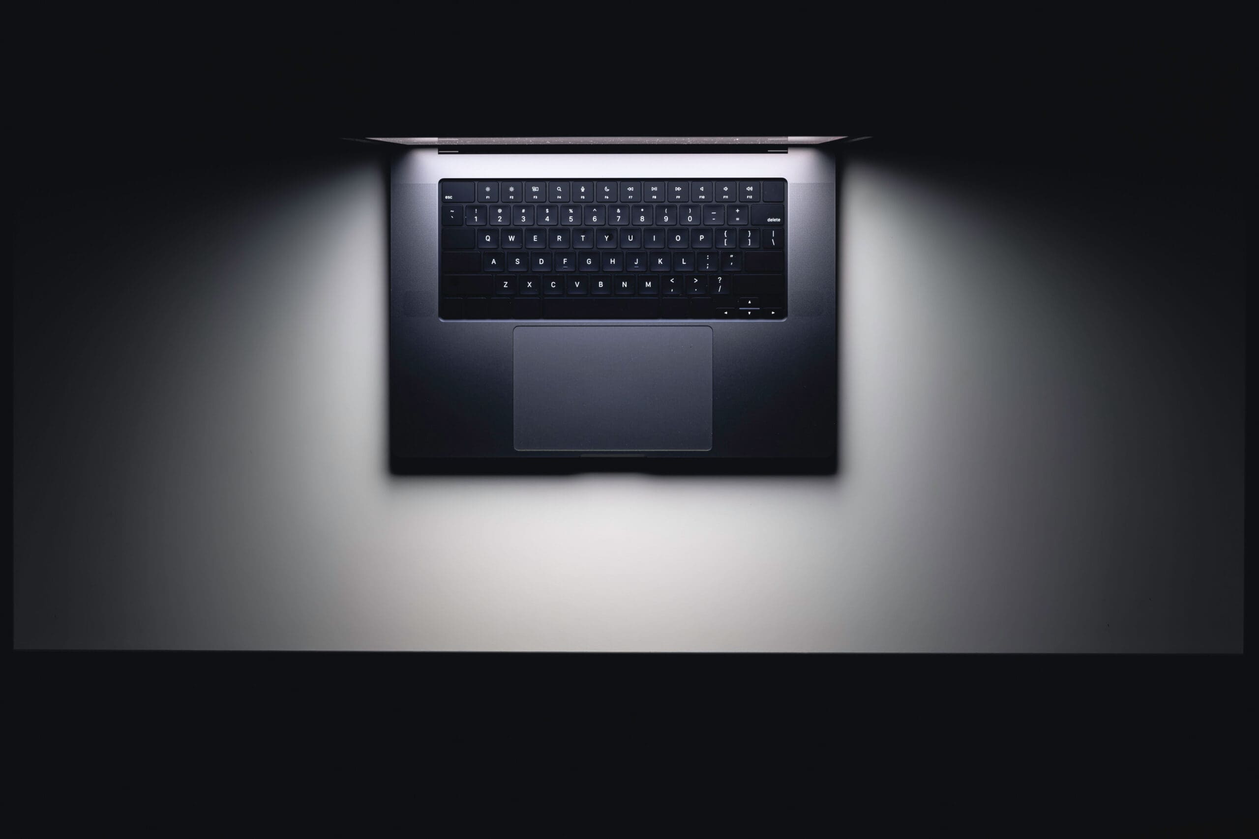 MacBook with glowing screen on a white table